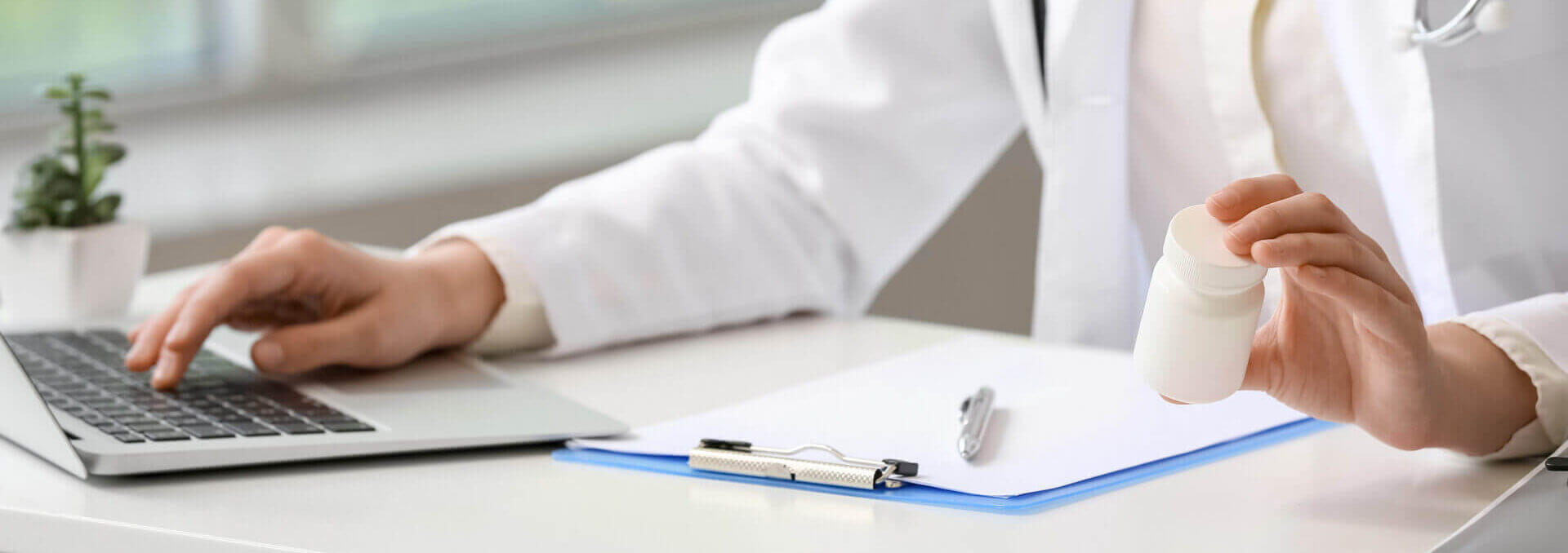 Female Doctor With Vitamins Using Laptop In Clinic, Closeup
