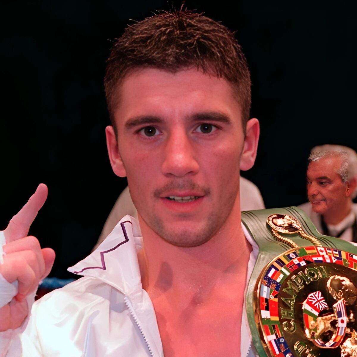Wayne “Pocket Rocket” McCullough wearing a championship belt, pointing upward in victory after a match, symbolizing strength and resilience.